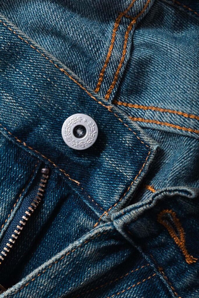 Close-up of denim jeans details, including the button.